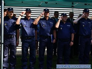 Policjanci w mundurach oddający honor