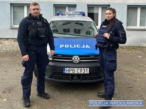 Stojący przy radiowozie dwaj umundurowani funkcjonariusze Policji