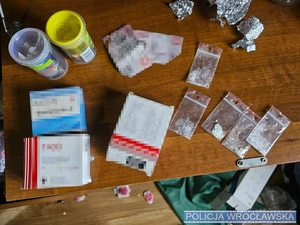 Leżące na stole narkotyki w woreczkach foliowych oraz leki w oryginalnych opakowaniach