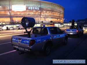 Zaparkowane przy stadionie oznakowane policyjne radiowozy.