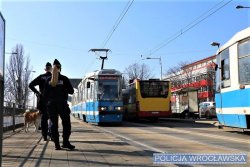 Umundurowani policjanci stojący na przystanku i oczekujący na tramwaj