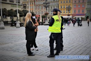 Umundurowani policjanci podczas rozmowy z obywatelami na wrocławskim rynku