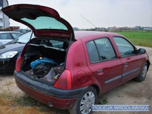 Pojazd osobowy marki Renault koloru czerwonego widoczne od tyłu, z otwartym bagażnikiem w którym widoczne są skradzione przedmioty