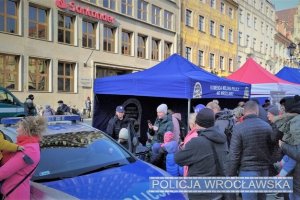 Zdjęcie przedstawia policyjne stoisko profilaktyczne na wrocławskim rynku