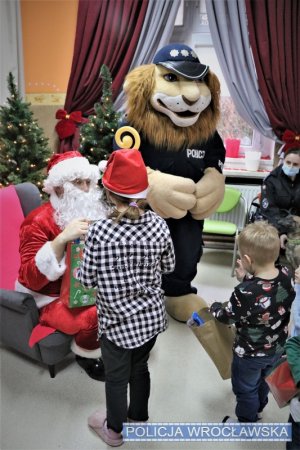 Święty Mikołaj oraz Komisarz Lew wręczający prezenty dzieciom