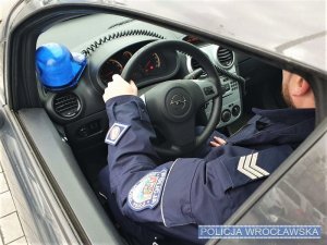 Policjant siedzący za kierownicą radiowozu
