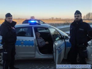 Policjanci oraz starsza kobieta siedząca w radiowozie