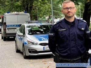 umundurowany policjant na tle oznakowanych radiowozów