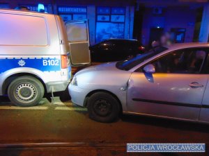 Osobowe auto i oznakowany radiowóz stojący na jednej z wrocławskich ulic