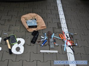 Narzędzia, radio oraz części samochodowe leżące na parkingu