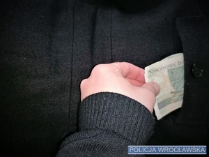 Dłoń wyciągająca pieniądze z kieszeni