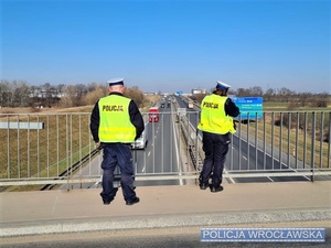 Dwóch funkcjonariuszy stojących na wiadukcie nad autostradą