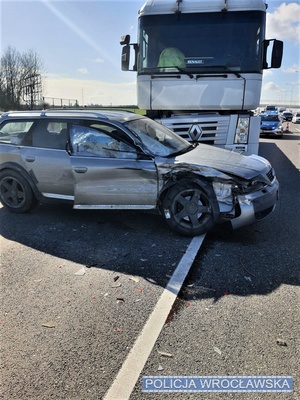 Zdjęcie zdarzenia drogowego, na którym widać, na pierwszym planie, auto osobowe oraz pojazd ciężarowy z widocznymi uszkodzeniami stojące na jezdni