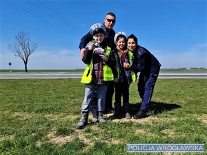 Dzieci w czapkach policjantów ruchu drogowego wraz z umundurowanymi funkcjonariuszami