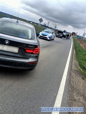 Stojące na jezdni oznakowane oraz nieznakowane radiowozowy oraz osobowy pojazd marki mitsubishi oraz stojący na jezdni umundurowani policjanci