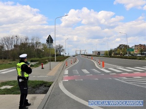 Stojący na drodze funkcjonariusz z ręcznym miernikiem prędkości w rękach