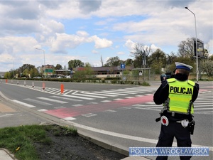 Stojący na drodze funkcjonariusz z ręcznym miernikiem prędkości w rękach