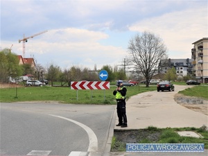 Stojący na drodze umundurowany policjant z ręcznym miernikiem prędkości w rękach