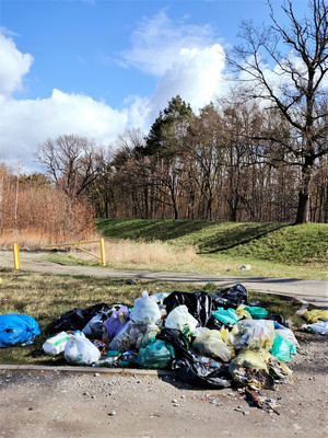 Zdjęcie odpadów w workach leżących na ziemi w okolicy wałów