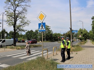 Dwaj umundurowani funkcjonariusze stojący przy przejściu dla pieszych na jednej z wrocławskich ulic