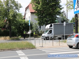 Dwaj umundurowani funkcjonariusze stojący przy przejściu dla pieszych na jednej z wrocławskich ulic