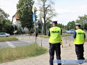 Dwaj umundurowani funkcjonariusze stojący przy przejściu dla pieszych na jednej z wrocławskich ulic