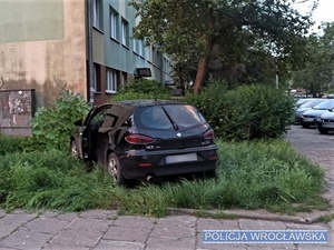 Stojące na trawniku przy bloku auto osobowe