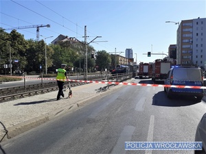 Umundurowana funkcjonariuszka oraz oznakowany radiowóz i wóz straży pożarnej na jednej z wrocławskich ulic w miejscu zdarzenia drogowego