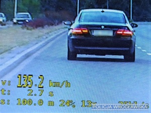 Zdjęcie wyświetlacza monitoru z widocznym pojazdem marki BMW i wynikiem dokonanego pomiaru prędkości