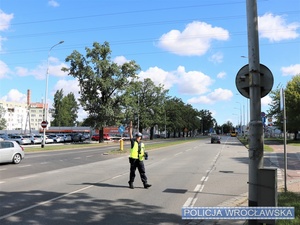 Policjant stojący na jezdni dający znak do zatrzymania się do kontroli