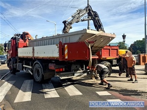 Stojący na jezdni pojazd ciężarowy, na które załadowywany jest ładunek