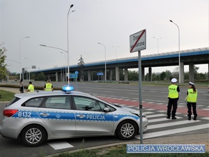 Stojący na jednej z wrocławskich ulic, przed oznakowanym radiowozem dwaj umundurowani funkcjonariusze ruchu drogowego