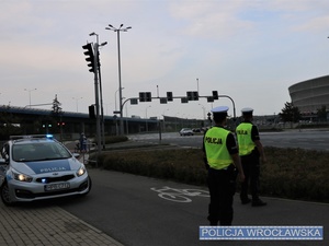 Stojący na jednej z wrocławskich ulic, przed oznakowanym radiowozem dwaj umundurowani funkcjonariusze ruchu drogowego