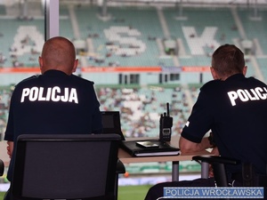 Policjanci w mundurze na tle murawy stadionu