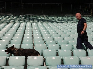 Policjant w mundurze z psem służbowym na trybunach stadionu