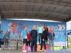 scena podium ze sportowcami oraz policjant w mundurze wręcza nagrody