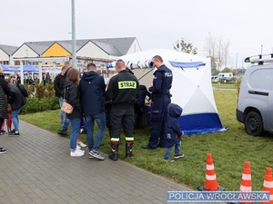 Stoisko policyjne z ludzmi przed oraz z policjantami w mundurze