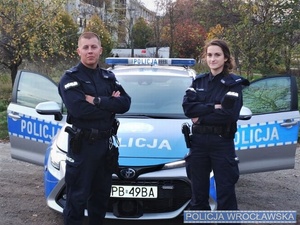 Policjantka i policjant z Komisariatu Policji Wrocław-Stare Miasto stojący przy radiowozie