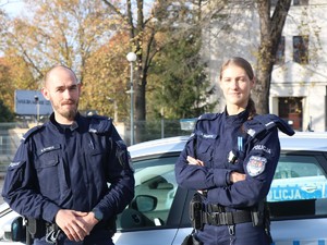 Policjanci w mundurze stojący na tle radiowozu