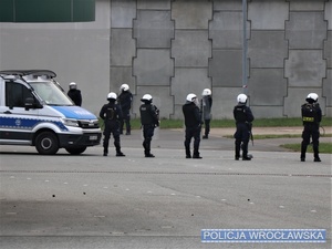 Stojący przy oznakowanym radiowozie przed stadionem umundurowani policjanci