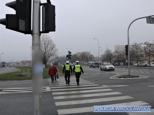 Dwaj umundurowani policjanci ruchu drogowego na przejściu dla pieszych, na jednej z wrocławskich ulic.