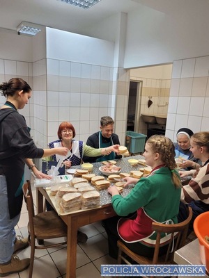 Kobiety, siostra zakonna i chłopiec robiący kanapki przy stole
