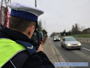 Funkcjonariusz policji Wydziału Ruchu Drogowego komendy miejskiej wykonujący pomiar prędkości na jednej z ulic w podwrocławskiej miejscowości