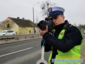 Funkcjonariusz Wydziału Ruchu Drogowego wrocławskiej komendy miejskiej podczas wykonywania pomiaru prędkości w jednej z podwrocławskich miejscowości - zdjęcie poglądowe