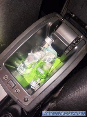 Butelki szklane z przeźroczystym płynem w schowku pojazdu