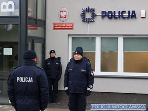 Policjanci w mundurze stoją przed budynkiem posterunku w Kamieńcu Wrocławskim