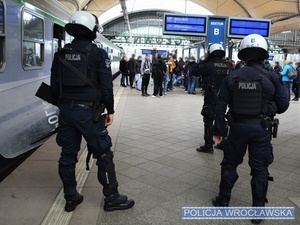 Umundurowani policjanci na jednym z peronów Dworca Głównego PKP we Wrocławiu oraz grupa kibiców