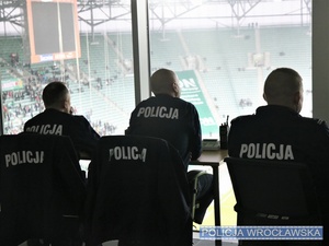 Umundurowani funkcjonariusze w tym dowódca zabezpieczenia meczu obserwujący płytę stadionu