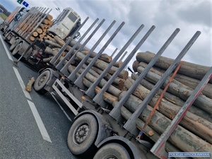 Zdjęcie pojazdu ciężarowego stojącego na jednej z podwrocławskich dróg z rozsypanym ładunkiem drewna leżącym na jezdni