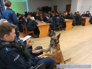 Spotkanie na sali młodzieżą ze szkoły mundurowej oraz policjanrt w mundurze z psem służbowym